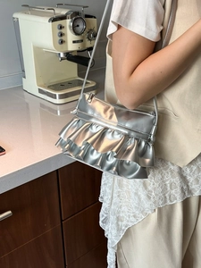 Metallic silver ballet-style crossbody bag with double-layered pleats and metal finish