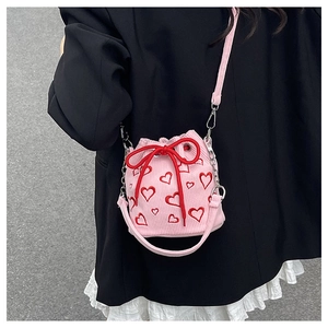 Détail d'un sac seau en velours rose avec broderie de coeurs rouges et fermeture à cordon