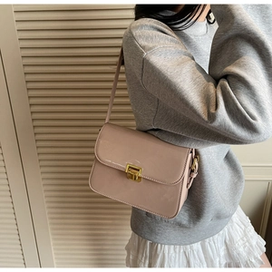 Detail of dusty pink patent leather shoulder bag featuring a gold twist lock and glossy finish