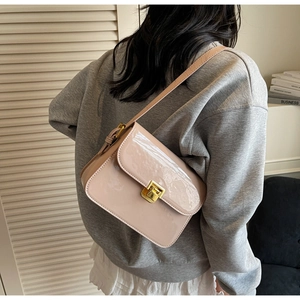 Detail view of pink patent leather handbag with gold square twist lock worn by model