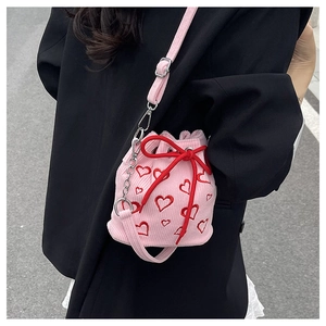 Détail du sac seau en velours rose avec broderies de cœurs rouges et chaîne