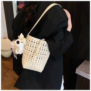 Détail du sac seau beige ajouré avec texture découpée au laser et pendentif peluche