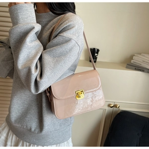 Detailed close-up of a nude pink patent leather crossbody bag with gold metal buckle