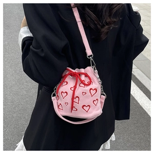 Détail du sac seau en velours rose avec broderie de coeurs rouges et cordon de serrage