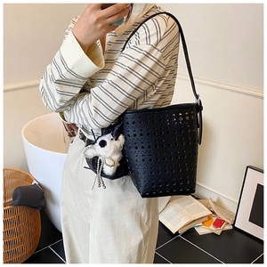 Détail du sac seau noir en cuir PU évidé avec un joli porte-clés en peluche blanche