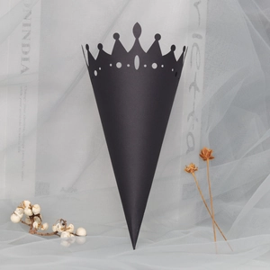 Close-up of black hollow crown paper cone with intricate cutout patterns for wedding petals