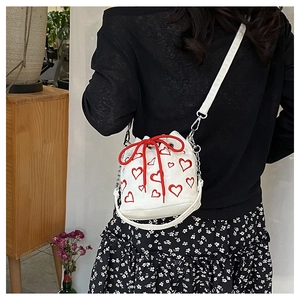 Détail du sac seau en velours blanc avec motifs cœurs rouges et fermeture à cordon