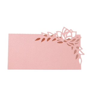 Macro detail of laser-cut rose hollow pattern on pink pearlescent paper place card