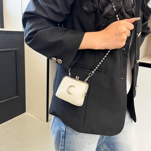 Mini white leather crossbody bag featuring a silver crescent moon buckle and ball chain