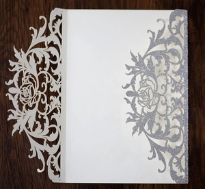Detail of laser-cut rose pattern wedding invitation with silver glitter finish