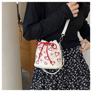 Détail du sac seau en velours côtelé blanc avec motifs de cœurs rouges et cordon