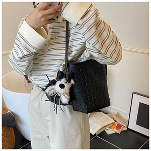 Détail du sac seau noir ajouré avec un pendentif chien en peluche dans un décor de style de vie