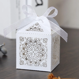 Détail de boîte à bonbons blanche découpée au laser avec motifs floraux et ruban organza