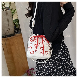 Détail du sac seau en velours côtelé blanc avec broderie cœur rouge et cordon de serrage