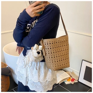 Détail du sac seau ajouré kaki avec un pendentif chiot en peluche dans un décor de maison