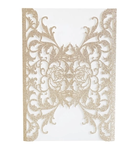 Close-up of laser-cut rose champagne gold glitter wedding invitation with floral patterns