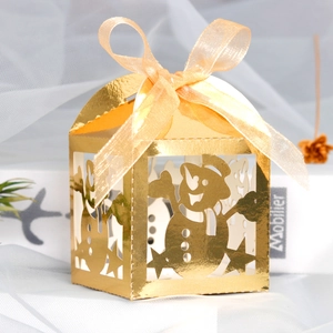 Close-up of golden laser-cut snowman gift box with champagne ribbon bow for Christmas