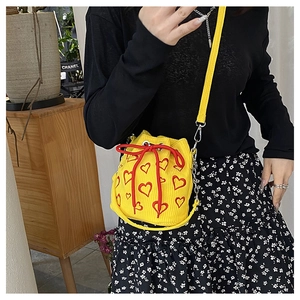 Détail du sac seau en velours côtelé jaune avec motifs cœurs rouges et cordon de serrage