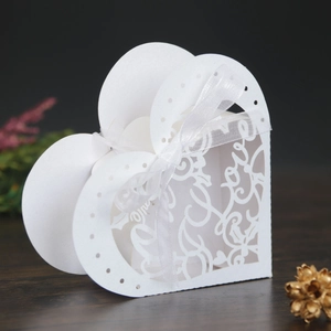 Detailed laser-cut heart favor box with Love script and white ribbon on wood