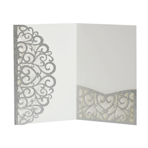 Macro shot of white laser-cut wedding invitation cover with silver glitter patterns