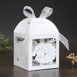 Close-up of white laser-cut candy box with sheep and heart patterns and silk ribbon