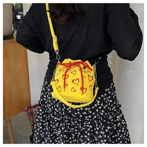 Détail du sac seau en velours côtelé jaune avec motif cœur rouge et cordon de serrage