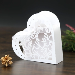 Detailed macro shot of white heart-shaped laser-cut wedding favor box with Love text
