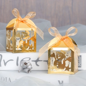 Detail of laser-cut snowman candy boxes in gold pearlescent paper with organza ribbons