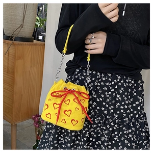 Détail du sac seau en velours côtelé jaune avec broderies cœurs rouges et nœud