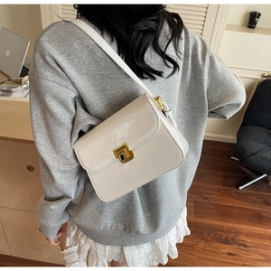 Detailed side view of a white patent leather shoulder bag with a gold metal clasp buckle