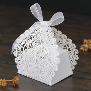 Macro shot of white laser-cut lace wedding favors box with a silky ribbon bow