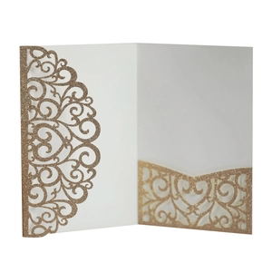 Macro shot of laser-cut glitter paper wedding invitation with ornate scroll patterns
