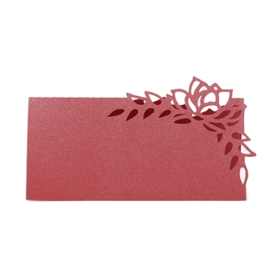 Macro shot of laser-cut red rose floral pattern on pearlescent paper wedding place card