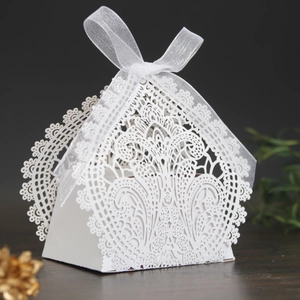 Macro shot of white laser-cut floral lace pattern on a triangular wedding favor box