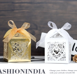 Close-up of laser-cut heart candy boxes with ribbon bows on a wooden background