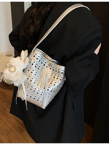 Sac seau argenté ajouré avec pendentif en peluche sur fond de veste noire