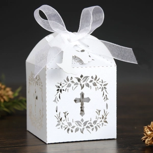 Detailed laser-cut white favor box with cross motif and white organza ribbon bow