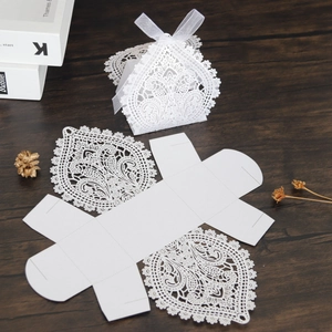 Close-up of laser-cut hollow lace candy box with white ribbon and flat-lay structure