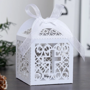 Détail d'une boîte à dragées blanche découpée au laser avec motif de croix et ruban
