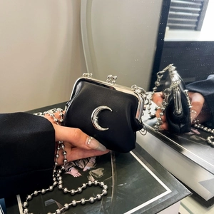 Close-up of a mini black leather coin purse featuring a silver moon charm and bead chain