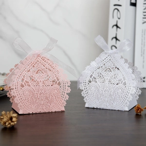 Detail of laser-cut lace pattern on pink and white gift boxes with silk ribbons