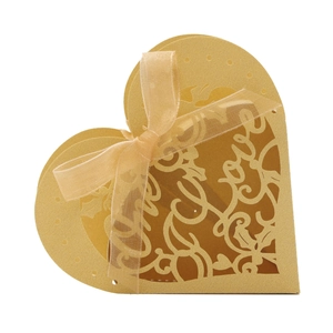 Macro view of gold laser-cut heart favor box featuring Love lettering and organza ribbon