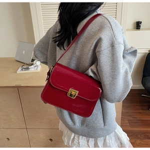 Detail of red patent leather crossbody bag with elegant gold buckle on a minimalist strap