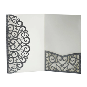 Detail of laser-cut glitter paper invitation with heart pattern and scrollwork