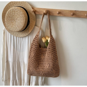 French style khaki knitted tote bag with hollow mesh design hanging on a wooden hook
