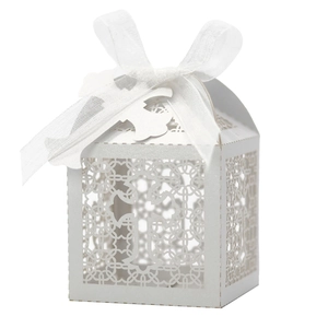 Close-up of white laser-cut hollow candy box with cross design and silk ribbon bow