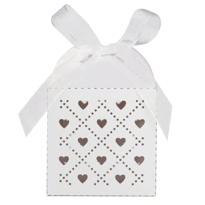 Close-up of white house-shaped laser cut favor box with heart patterns and silk ribbon
