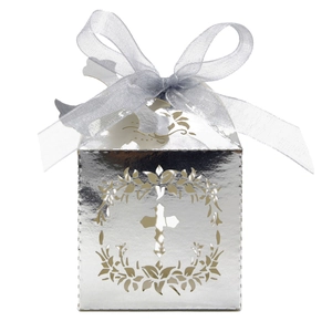 Close-up of silver hollow cross candy box with intricate floral pattern and ribbon bow