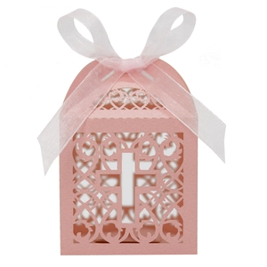 Détail boîte cadeau rose ajourée au laser avec motif croix et élégant ruban en organza