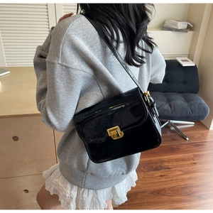 Close-up of black patent leather crossbody bag featuring a luxury gold square twist lock